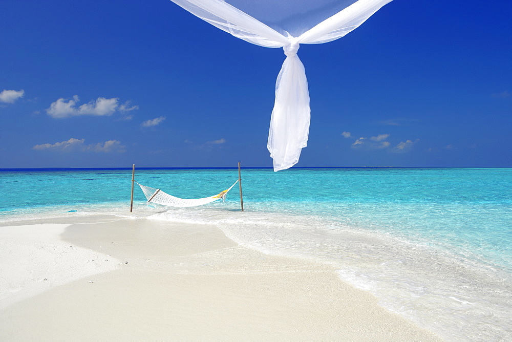 Hammock hanging in shallow clear water, The Maldives, Indian Ocean, Asia