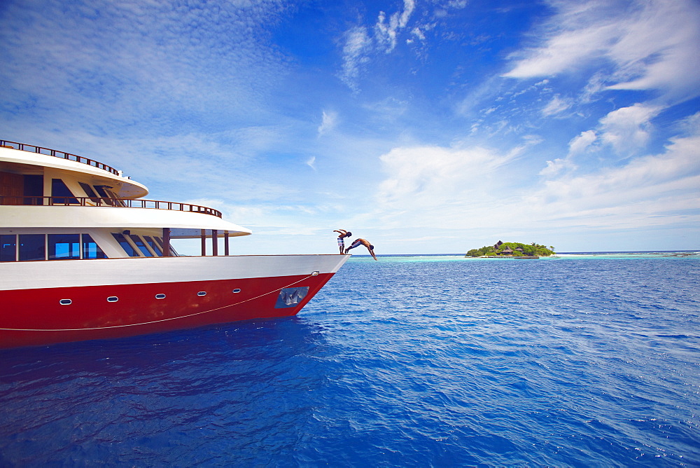 Young people jumping from boat into sea, Maldives, Indian Ocean, Asia