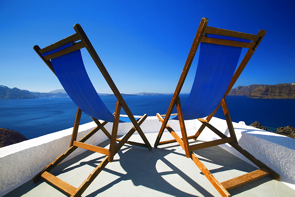 Deck chairs on terrace overlooking ocean, Santorini, Cyclades, Greek Islands, Greece, Europe