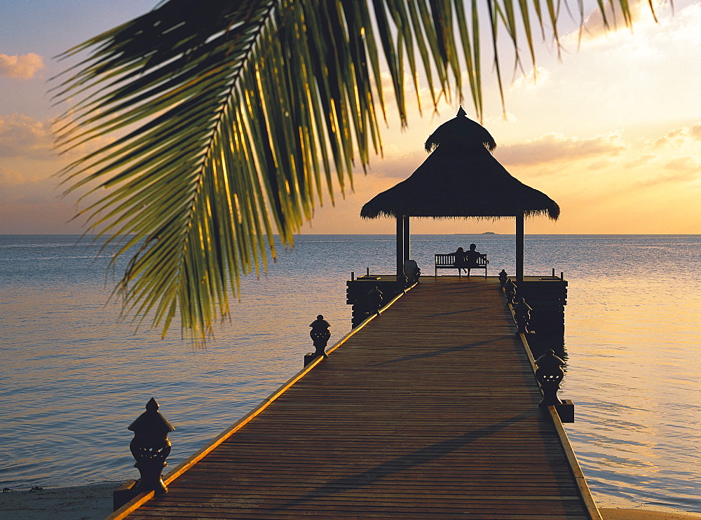 Couple looking at sunset on a jetty, Maldives, Indian Ocean, Asia