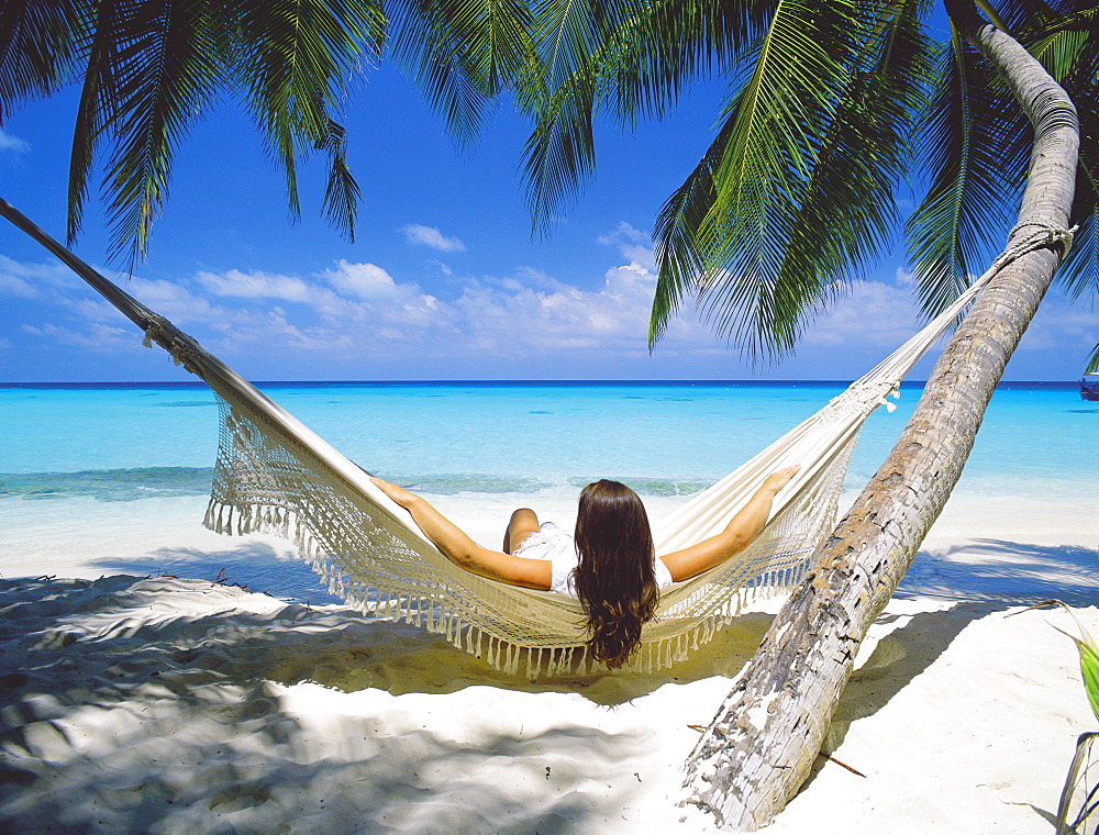 Woman sitting in hammock on beach, Maldives, Indian Ocean, Asia