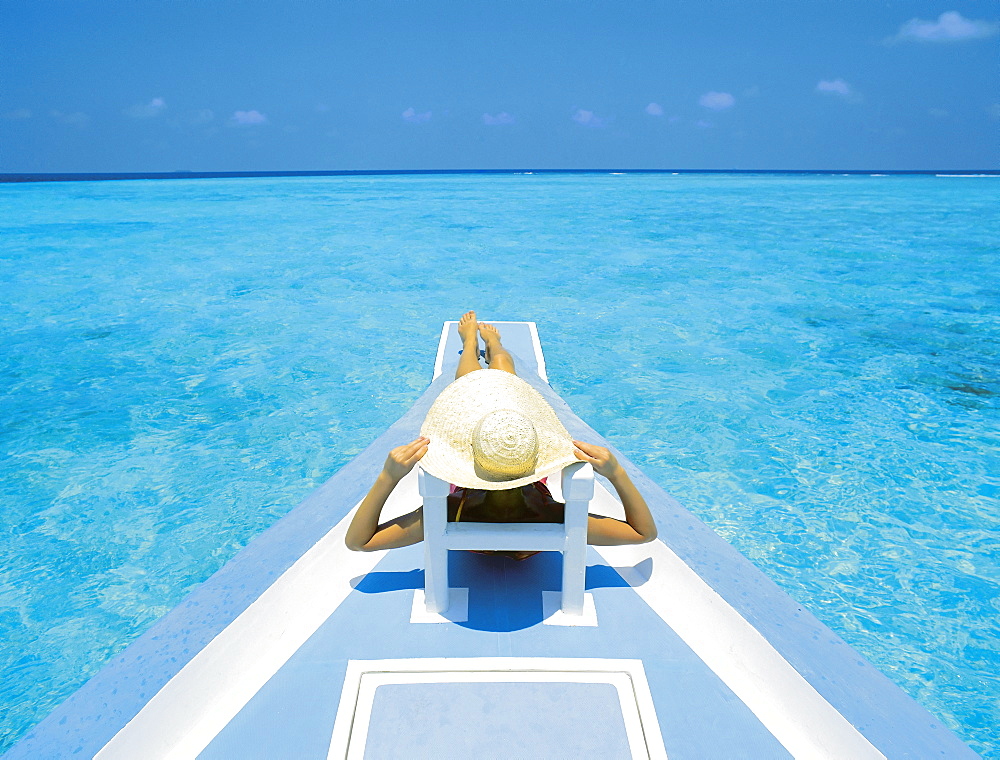 Woman relaxing on deck of boat, Maldives, Indian Ocean, Asia