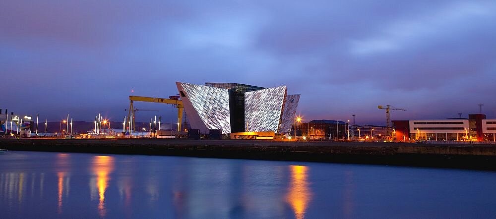 Ireland, North, Belfast, Titanic Quarter, Visitor centre designed by Civic Arts & Eric R Kuhne, illuminated at night.