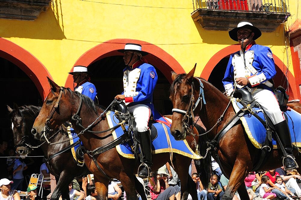 Mexico, Bajio, San Miguel de Allende, Independence Day celebrations. Re-enactment of the Call for Independence horsemen ride through street with watching crowd.