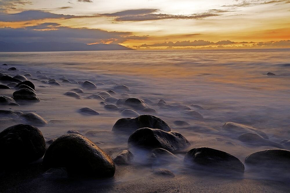 Mexico, Jalisco, Puerto Vallarta, Waves and rocks on beach at sunset.