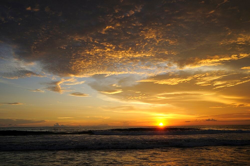 Mexico, Oaxaca, Puerto Escondido , Puerto Escondido Sunset over Playa Zicatela with waves breaking on shore.