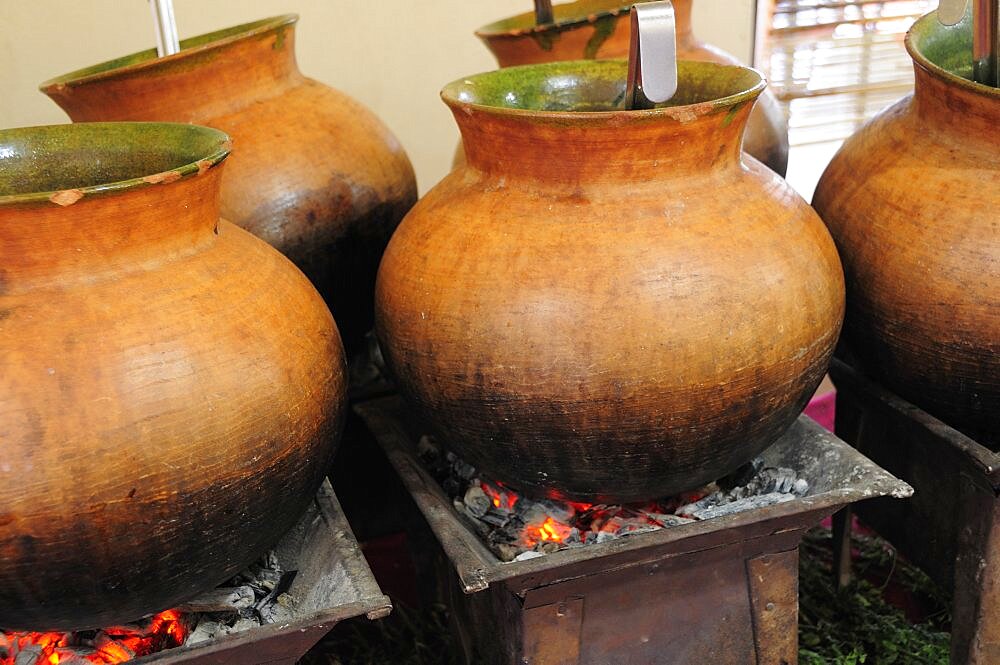 Mexico, Oaxaca, Large earthenware pots of food cooking over hot coals.