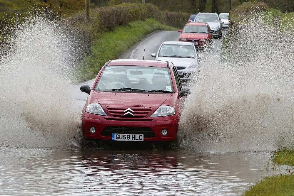 England, Kent, Flooding, Flooded country road with cars driving slowly through waters.