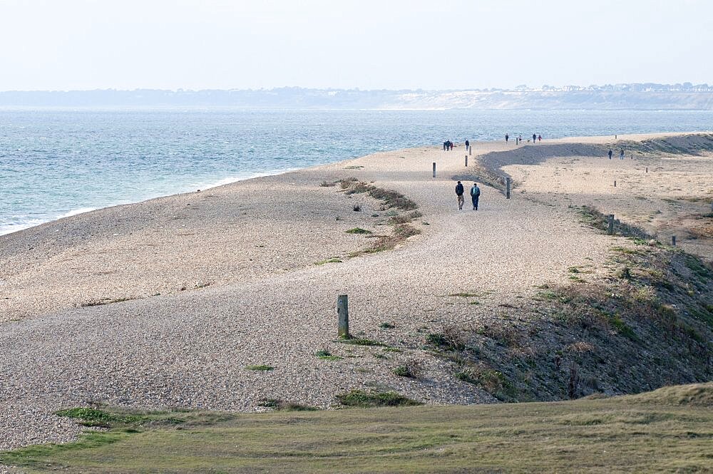 England, Hampshire, Milford on Sea, People walking along Hurst spit a 1.5 mile long shingle ridge.