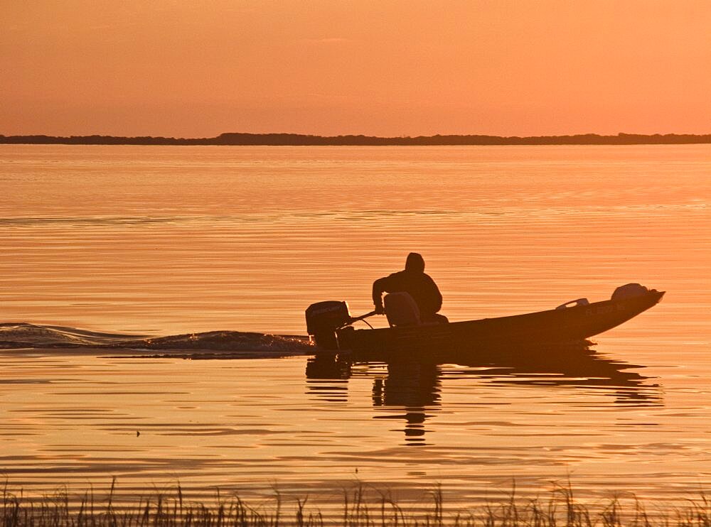 USA, Florida, Fisherman in his motorboat at Sunset.