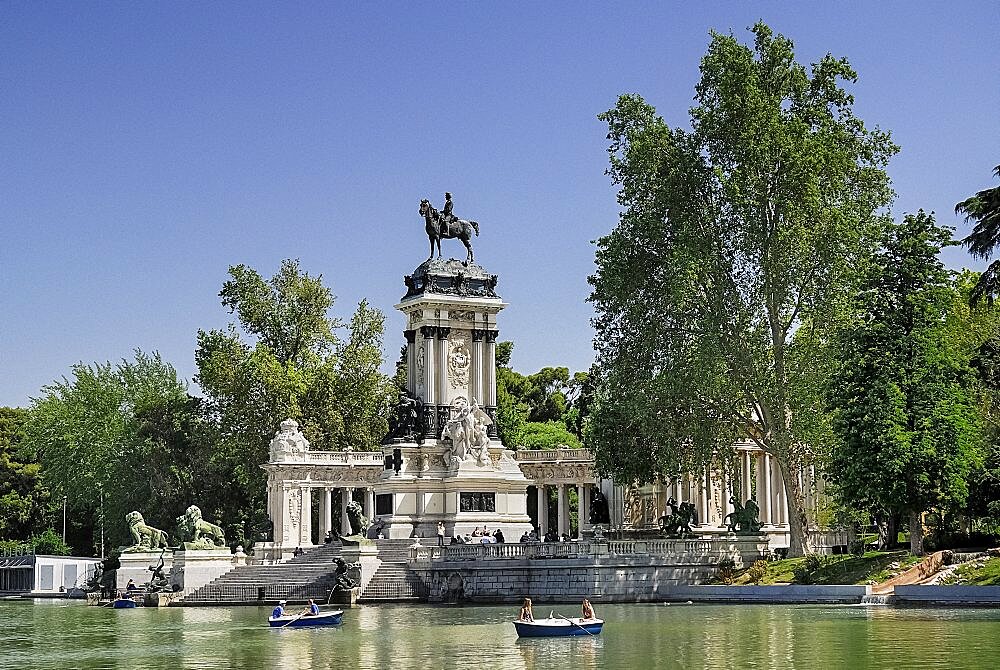 Spain, Madrid, Monument to King Alfonso XII in Parque El Buen Retiro with tourist boating inthe lake.