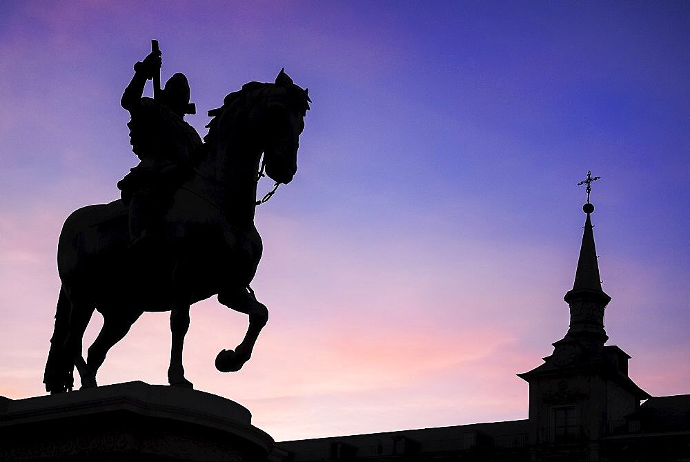 Spain, Madrid, Statue of King Philip II in Plaza Mayor silhouetted against evening sky.