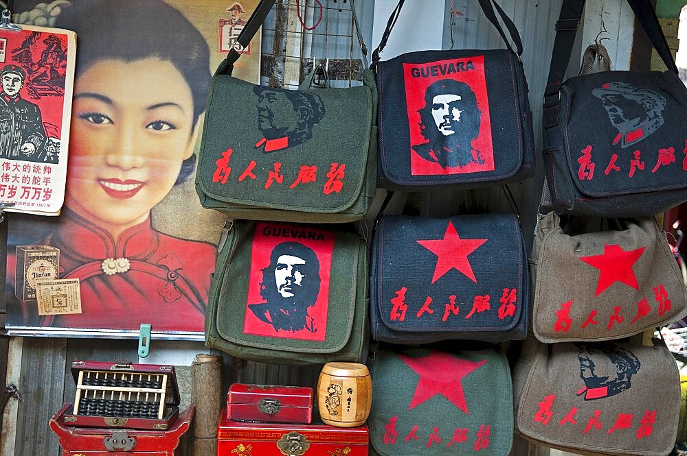 China, Shanghai, Revolutionary kitsch on sale at at Dongtai antique market Chairman Mao Zedong and Che Guevara and Red Star shoulder bags Chinese characters read Serve the People Lin Biao calendar atop Shanghai Belle advertizing poster Fake antique boxes and abacus.