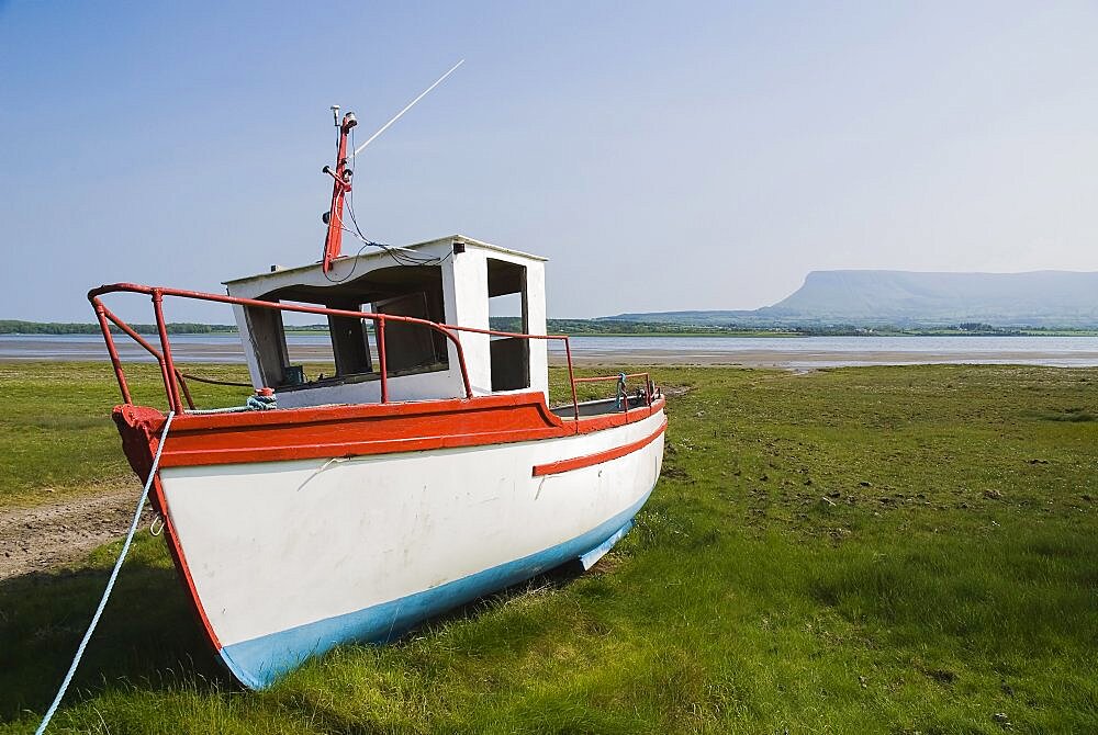 Ireland, County Sligo, Rosses Point, Boat moored on the 3rd beach with Ben Bulben in the background.