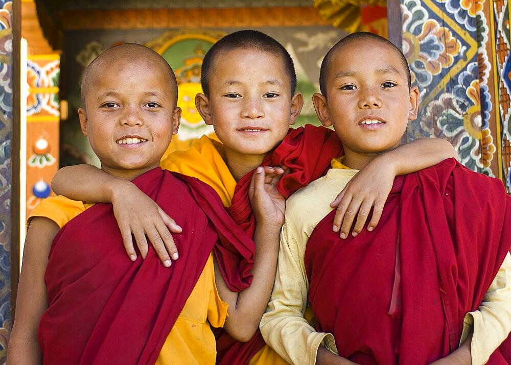 Bhutan, Punakha, Three young novice monks standing in doorway of Chimi Lakhang temple in the old capital.