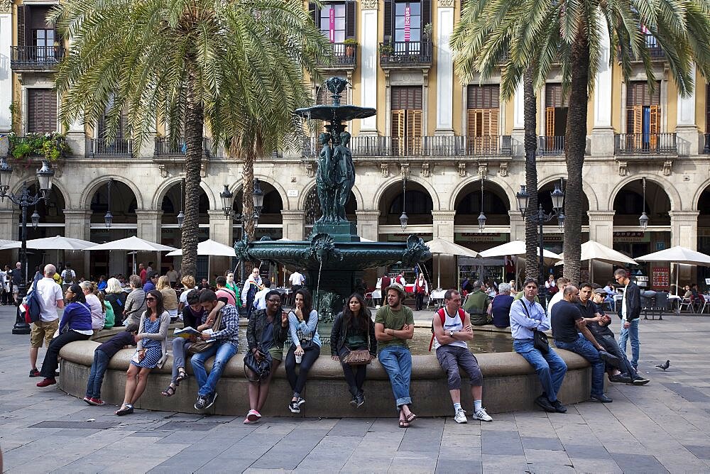 Spain, Catalonia, Barcelona, Tourists sat around the fountain in Placa Reial.