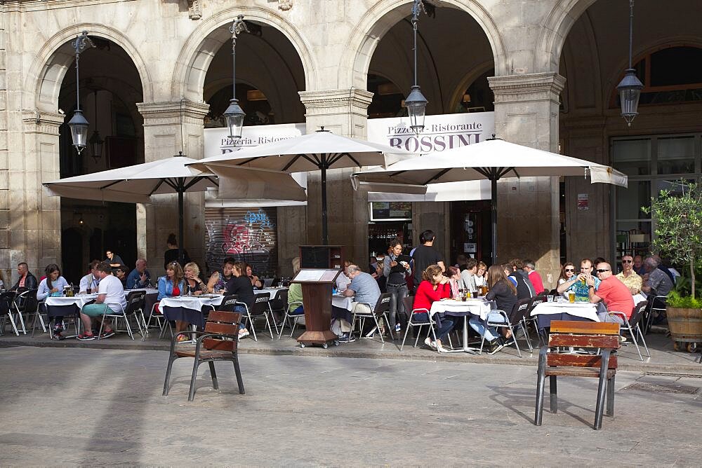 Spain, Catalonia, Barcelona, Tourists sat at tables outside cafe in Placa Reial.