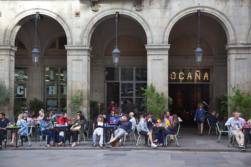 Spain, Catalonia, Barcelona, Tourists sat at tables outside cafe in Placa Reial.