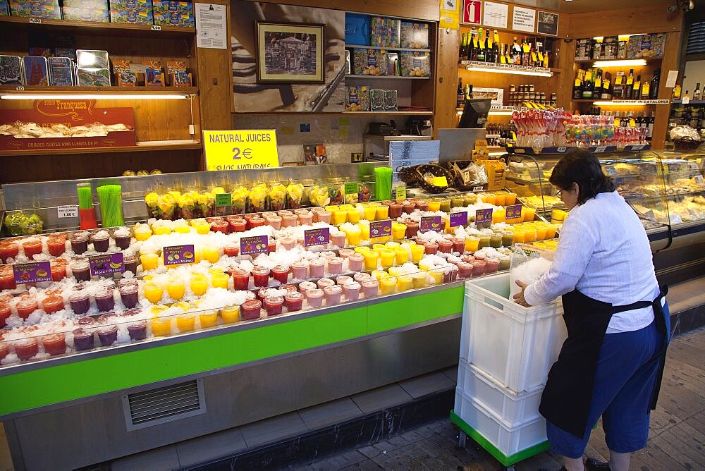 Spain, Catalonia, Barcelona, Fresh fruit juice vendor covering drinks in crushed ice.