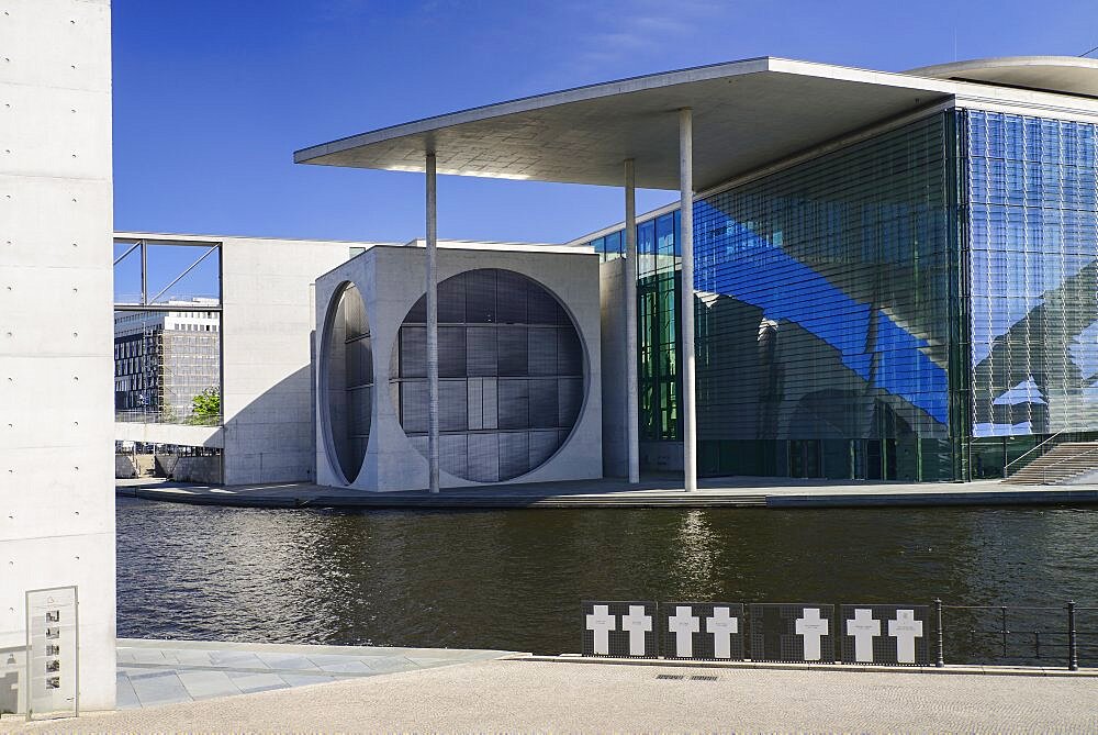 Germany, Berlin, Marie Elisabeth Luders Haus which is a service centre of the Bundestag located across the River Spree behind the Reichstag with memorial crosses to Berlin Wall victims in the foreground.