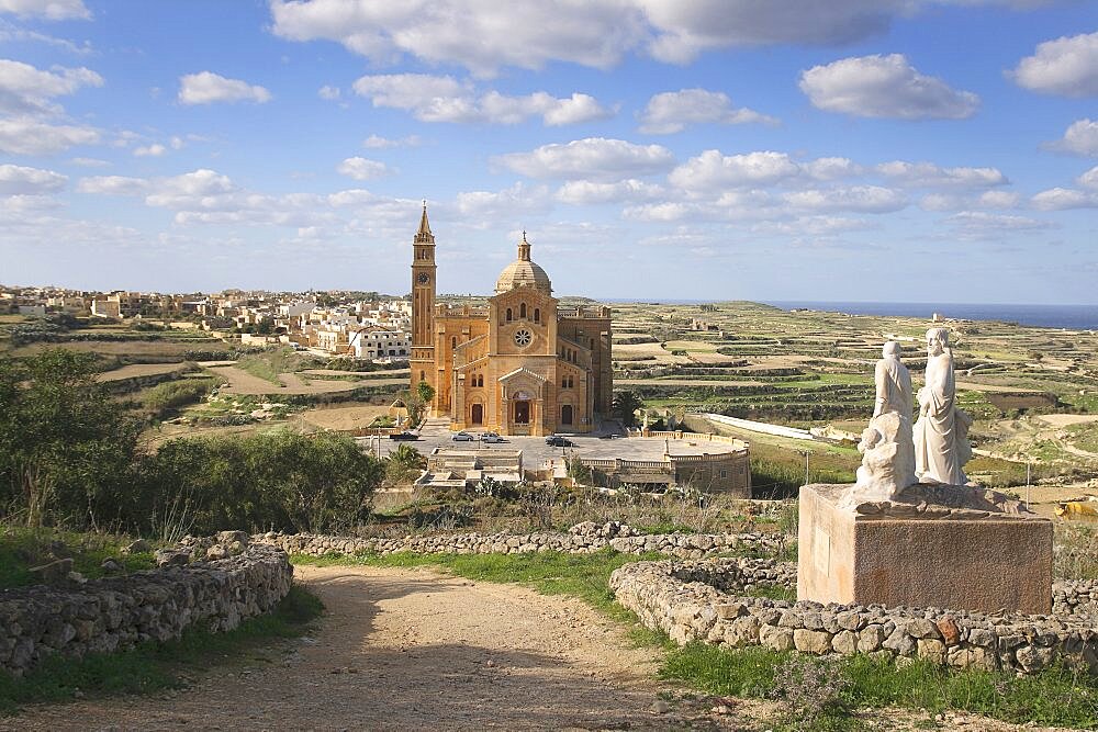 Malta, Gozo, Ta Pinu, Sanctuary church seen form hilltop with statues in the foreground.