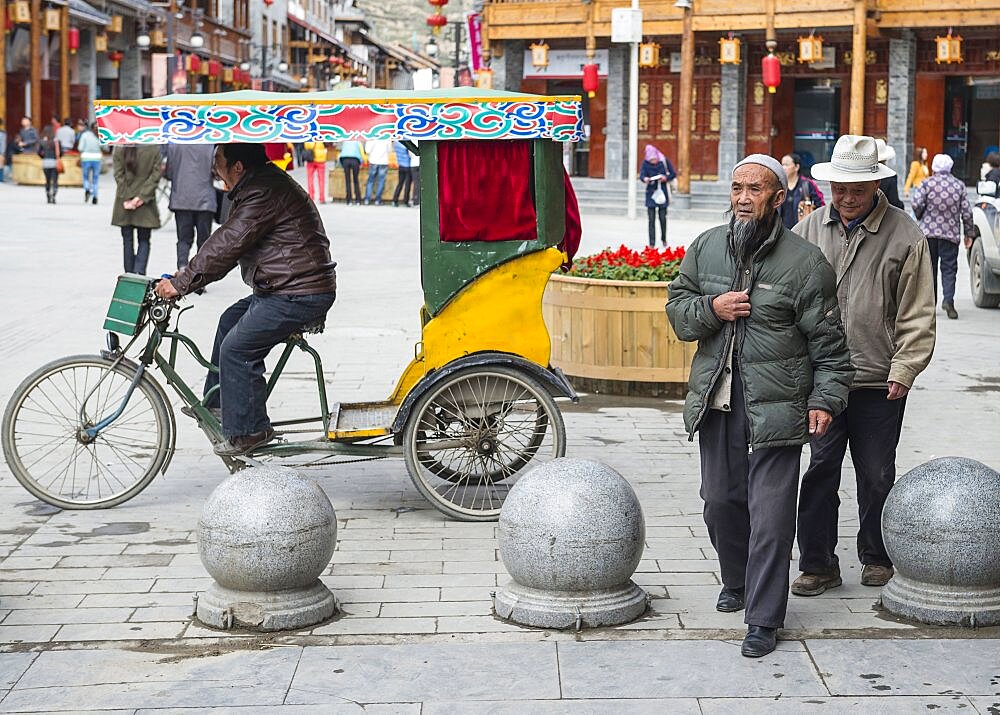 China, Sichuan, Songpan, Yawning trishaw driver and walking aged citizens.