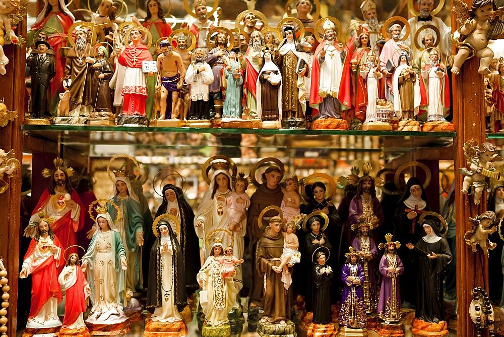 Spain, Madrid, Religious statues and icons on display in shop window.