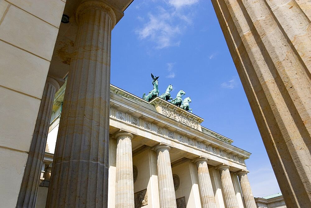 Germany, Berlin, Mitte, Brandenburg Gate or Brandenburger Tor seen between columns in Pariser Platz leading to Unter den Linden and the Royal Palaces with the Quadriga of Victory on top. The only remaining of the original 18 gates in the Berlin Customs Wall.