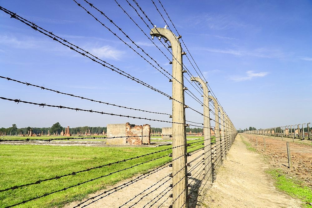 Poland, Auschwitz-Birkenau State Museum, Birkenau Concentration Camp, Ruins of former accommodation blocks surrounded by barbed wire fencing.