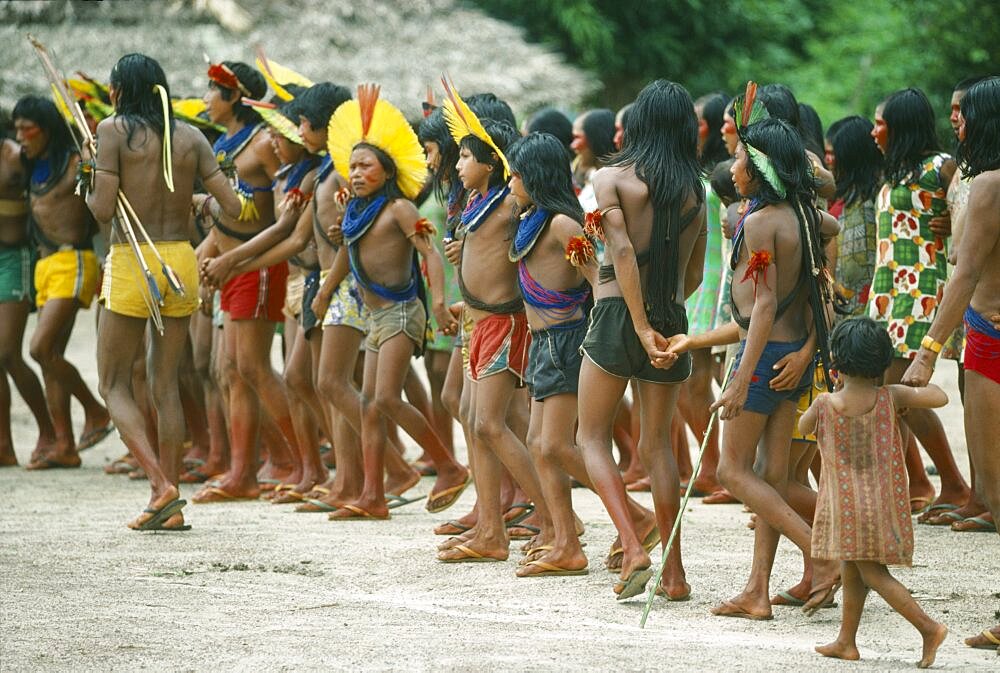 BRAZIL Amazonas General Group of Xikrin Indians wearing feather head dresses and bead jewellery and with their feet and faces painted with red urucu juice.  Brasil Kaiapo