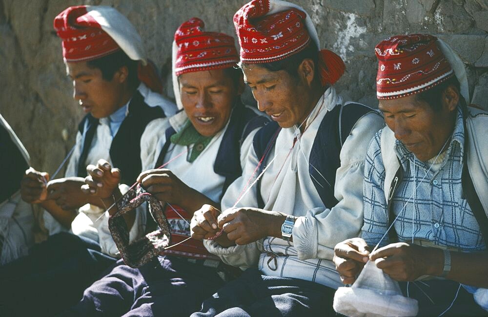 PERU Puno Lake Titicaca Taquile Island.  Line of men knitting.