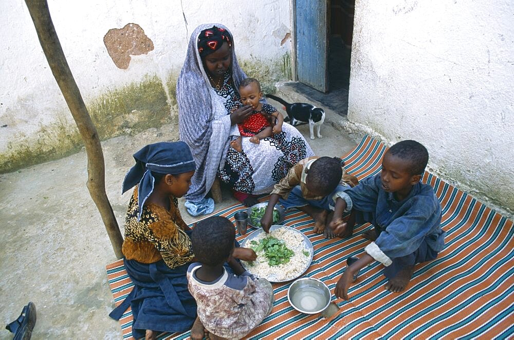 SOMALIA  Baidoa Woman and children eating lunch from communal dish using the right hand.  At a family meal men are usually served first and women and children eat seperately later.