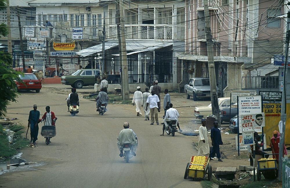 NIGERIA  Kano Street scene in the business district with people and traffic and criss crossing overhead cables. African Nigerian Western Africa