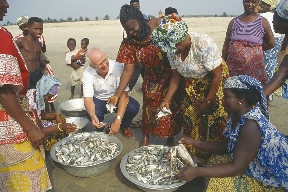 GHANA  People Western man talking to women selling fish on beach near Accra.