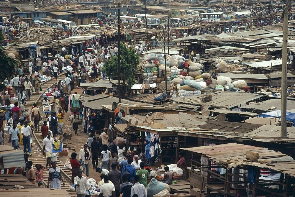 GHANA Ashanti Region Kumasi Busy market square with traffic  crowds of people and tin roofed open sided stalls.  Asante  West Africa