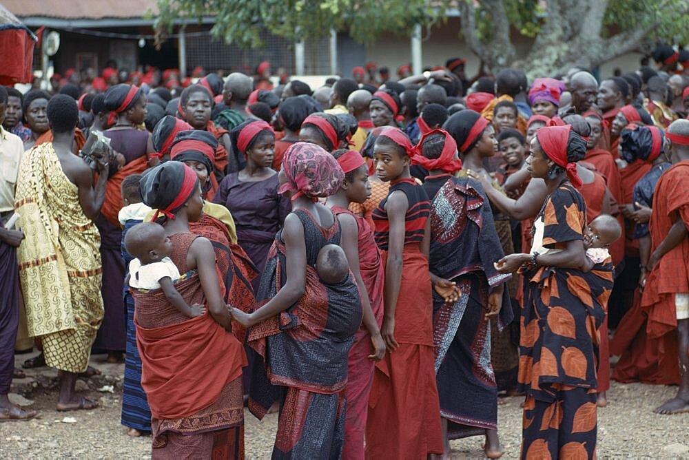 GHANA  Tribal People Group of women carrying babies on their backs at Ashanti funeral  dressed in red the colour of mourning.  Large mixed crowd in background. Asante Color