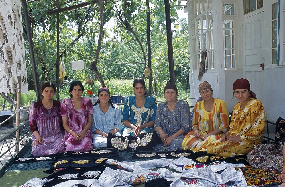 TAJIKISTAN  People Seven sisters sat in a row with fabric layed out in front of them.