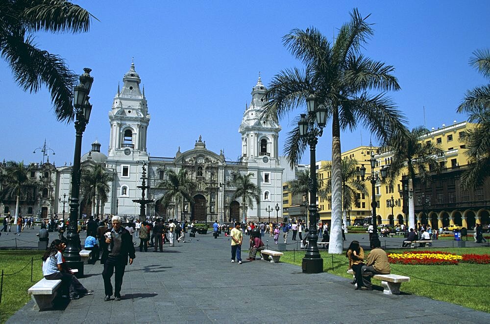 PERU  Lima Cathedral and Plaza de Armas   Plaza Mayor . Travel Tourism Holiday Vacation Explore Recreation Leisure Sightseeing Tourist Attraction Tour Destination Plaza De Armas Mayor Square Lima Peru Peruvian South America American Blue Sky Vivid Vibrant Tranquility Tranquil City Capital Tradition Traditional Culture Cultural Building Architecture Architectural Cathedral Church Churches Religion Religious Pray Prayer Worship Worshipping Worshiping Christianity Holy Divine Christian Theology Faith Sacred Devout Catholic Catholicism Magnificent Impressive Majestic Faade Landmark Dominant Dominating Prominent UNESCO World Heritage Site Palm Trees People Visitors Sightseers Busy Colonial Walking Sitting Strolling Relaxing Calendar South America