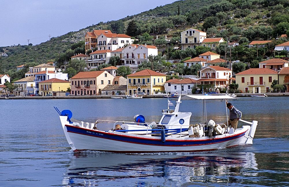 GREECE Ionian Islands Ithaca Vathi. Boat moving in harbour and Vathi town behind.  Travel Tourism Holiday Vacation Explore Recreation Leisure Sightseeing Tourist Attraction Tour Destination Vathi Ithaca Ithaka Ithica Ithika Ithaki Ithaci Greece Grecian Greek Ionian Sea Waterfront Waterside Water Calm Still Quiet Peaceful Picturesque Unspoiled Tranquility Tranquil Harbour Harbor Harbourside Harborside Hill Hillside Backdrop Vivid Vibrant Town Tradition Traditional Culture Cultural Community Buildings Houses Homes Residence Abode Dwellings Real Estate Property Apartments Fishing Boat Reflection Reflect Steep Man Gentleman Male Person Adult Fisherman Ethnic Business Work Working Worker Workplace Career Job Enterprise Enterprising Livelihood Occupation Moving Travelling Transport Transportation Foreground Interest Vacation Classic Classical Ellada Historical Male Men Guy Older Reflexion Southern Europe Traveling European History Male Man Guy