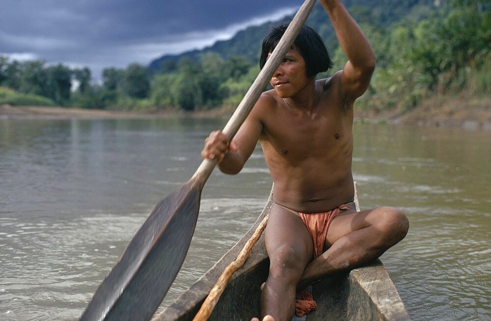 COLOMBIA Choco Embera Indigenous People Embera man using single oar to steer wooden dug out canoe along rio Baudo. Pacific coastal region boat piragua tribe