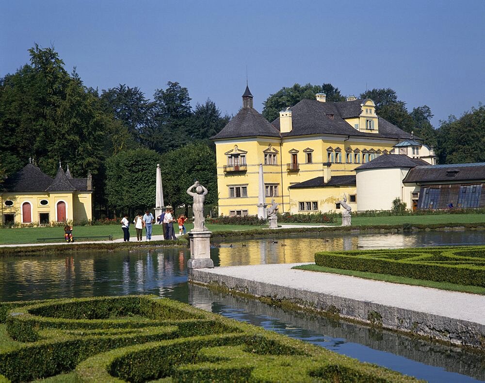 Hellbrunn Palace a yellow building behind an ornamental lake rimmed with boxed hedges, Salzburg, Salzburg Province, Austria