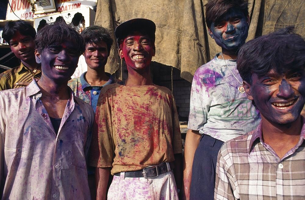 Group of young men with their faces covered with coloured powder paint dyes during Holi Festival, Delhi, India