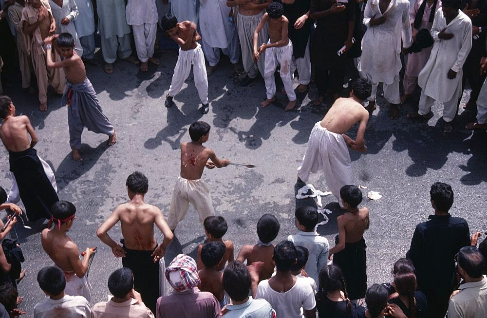 Mohurrum Shia muslim festival commemorating death of Husayn ibn Ali grandson of Muhammad, Boys beating themselves with chains in ceremonial mourning, Peshawar, Pakistan