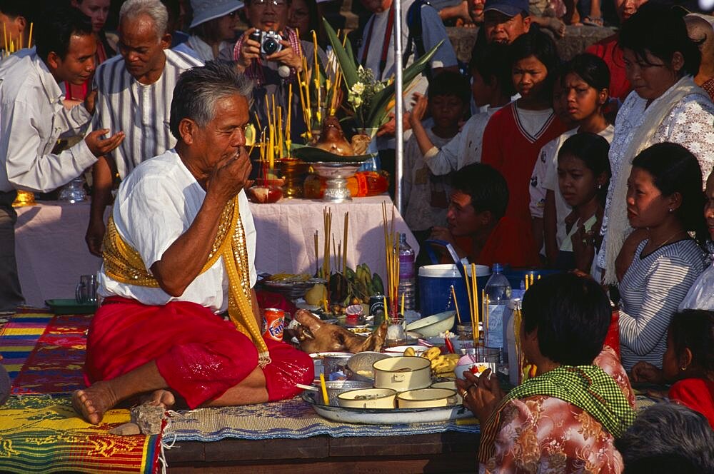 Shaman at ceremony smelling the offerings of food brought by the Khmer people, Angkor Wat, Siem Reap Province, Cambodia