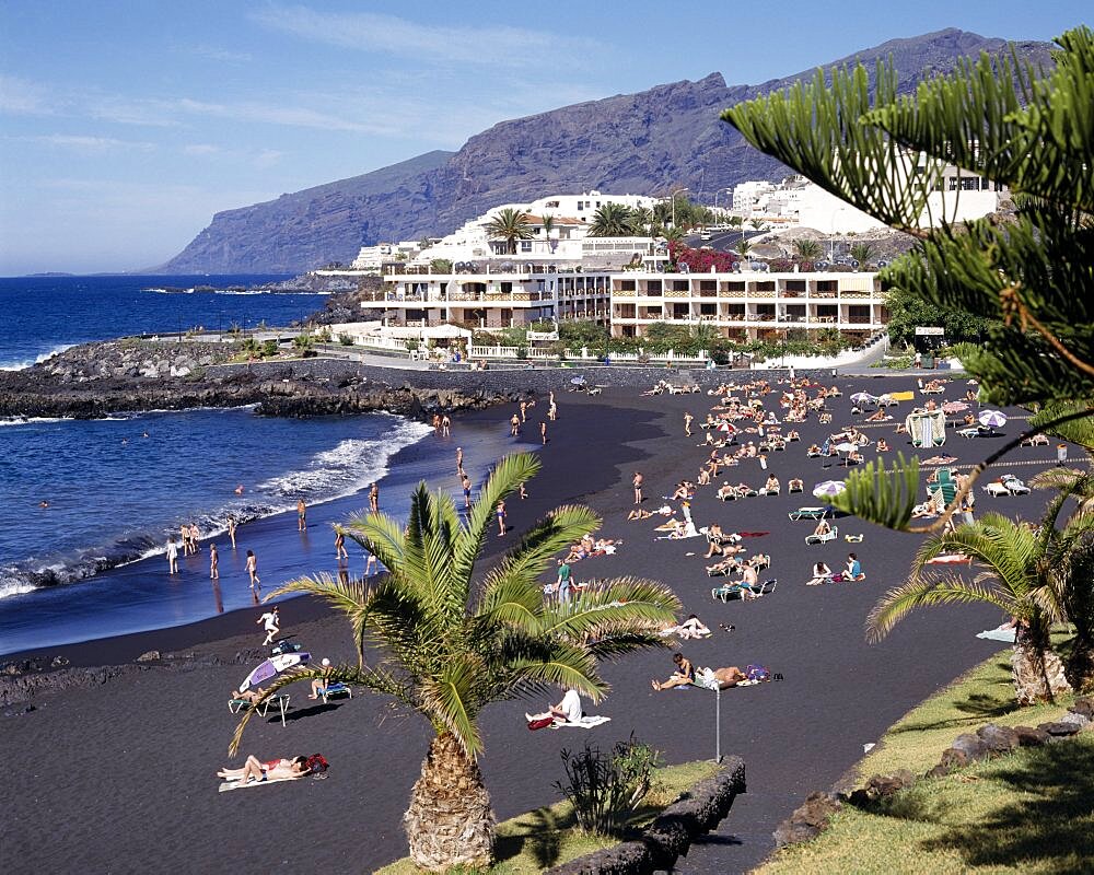 SPAIN Canary Islands Tenerife Playa de la Arena near Los Gigantes with sunbathers on black sandy beach and apartments in the distance