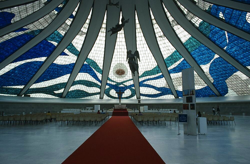 Cathedral Metropolitana interior with stained glass ceiling and suspended aluminium angels designed by Alfredo Scesciatte, People on seating in front of altar below, Brasilia, Brazil