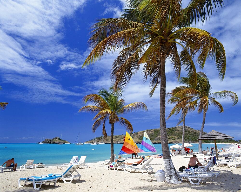 WEST INDIES  Antigua Deep Bay.  Sandy beach with sailing boats  sunbeds and palm trees.