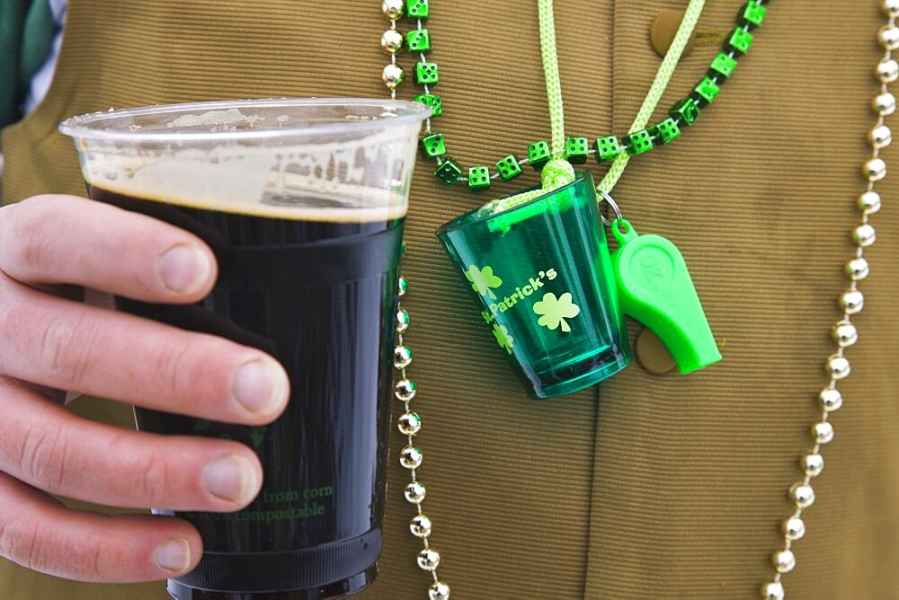 Detail of man wearing various green items whilst drinking pint of stout beer, St Patricks Day, Colorado, United States of America