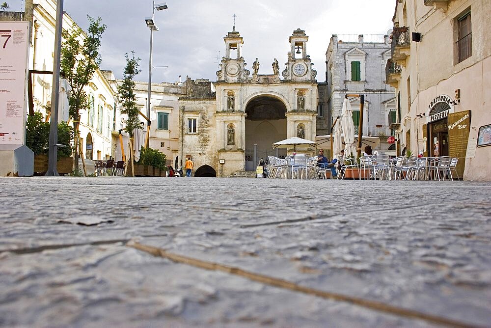 Main square in ancient city of Sassi di Matera or the Stones of Matera originating from a prehistoric cave settlement, UNESCO World Heritage Site, Cafe bar with outside seating overlooked by church and bell tower, Matera, Basilicata, Italy