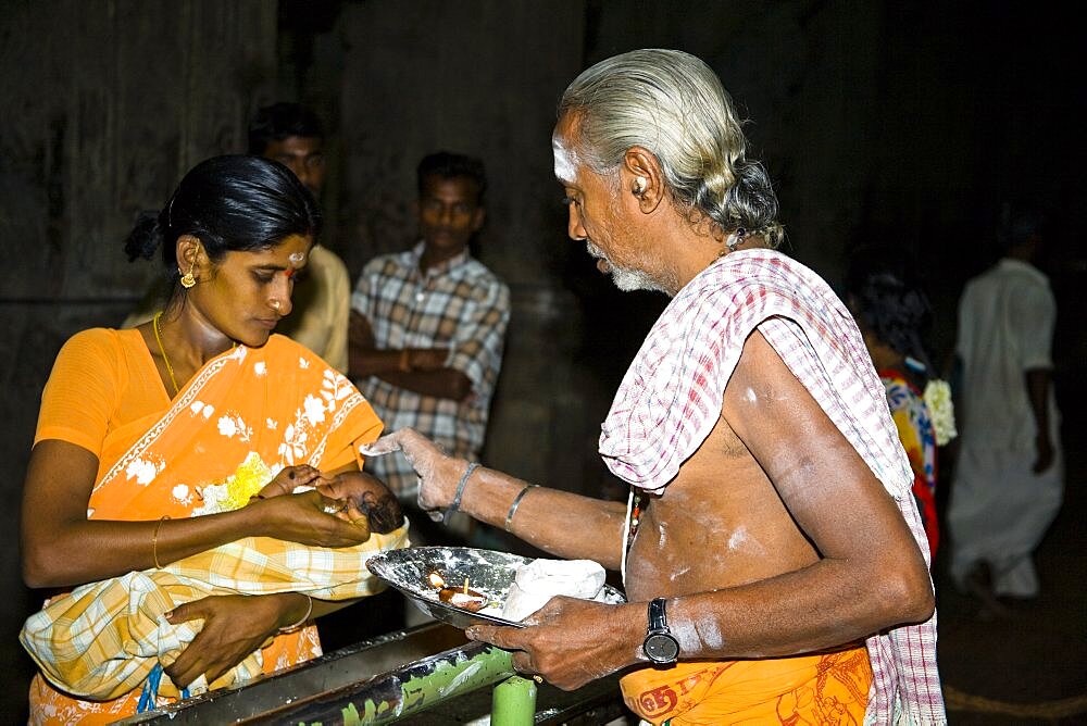 Brahmin blessing a baby, held in his mothers arms, Meenakshi Temple, Madurai, Tamil Nadu, India,